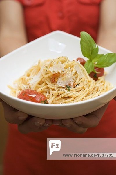 Hände halten Teller Spaghetti mit Parmesan und Basilikum