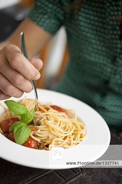 Frau isst Spaghetti mit Tomaten  Parmesan und Basilikum