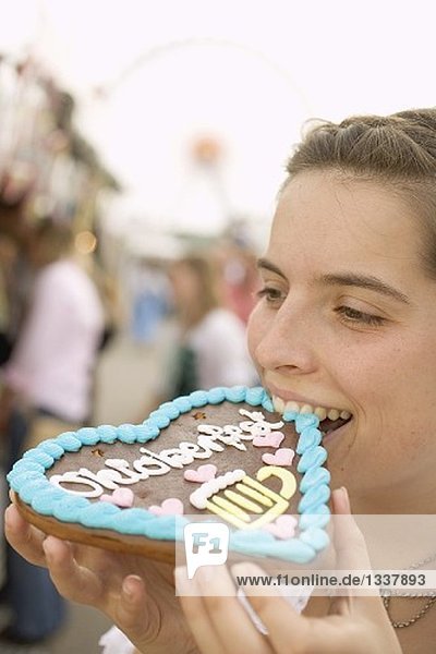 Frau beisst in Lebkuchenherz (München  Oktoberfest)