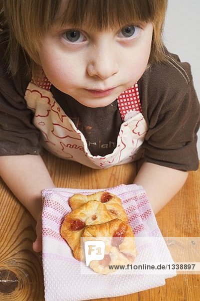 Kind hält frisch gebackene Blätterteigtaschen auf Tuch