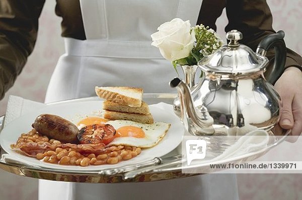 Zimmermädchen serviert englisches Frühstück auf Tablett