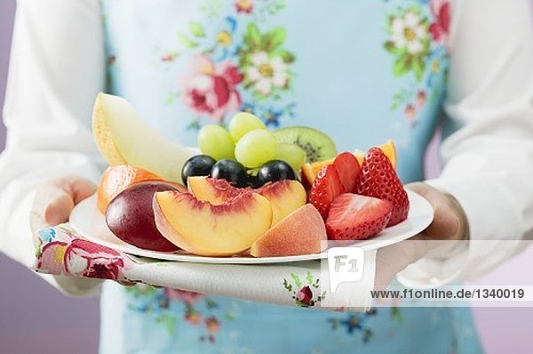 Frau serviert frische Früchte auf Teller