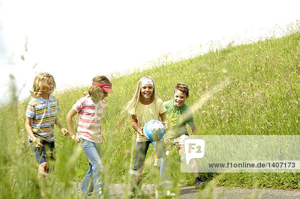 Vier Kinder spielen mit Ball auf Straße