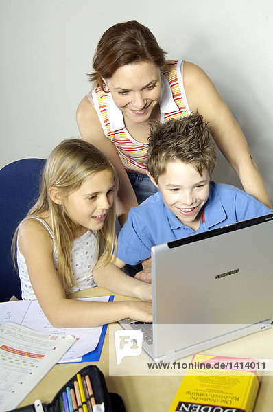 High Angle View of Frau blickt auf ihre beiden Kinder mit laptop