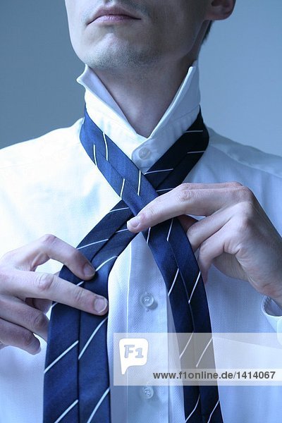 Close-up of businessman tying his tie