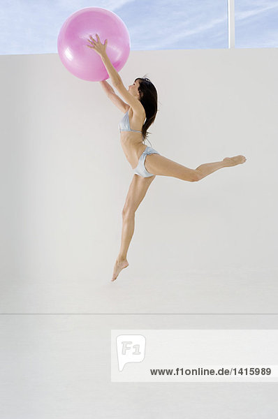 Young woman in bikini  jumping  holding big pink balloon