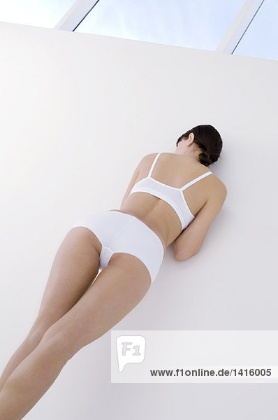 Young woman in underwear  leaning against wall