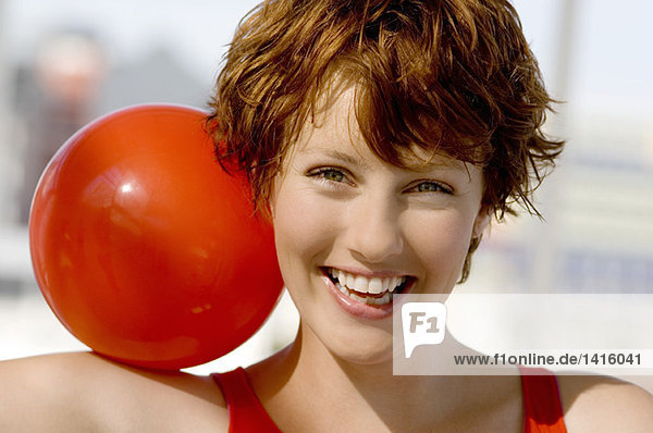Porträt einer jungen lächelnden Frau  roter Ball auf der Schulter