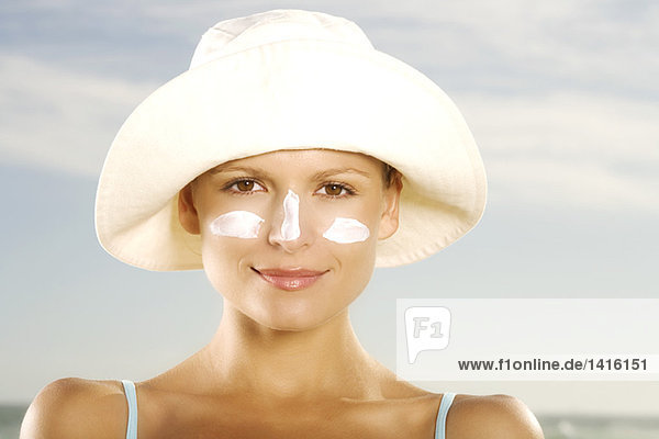 Portrait einer jungen Frau mit Sonnencreme im Gesicht