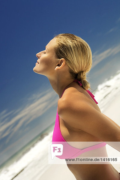Junge Frau in rosa Bikini am Strand  Kopf zurück  Augen geschlossen