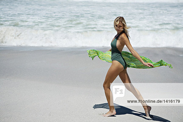 Young woman in swimming costume  walking on the beach