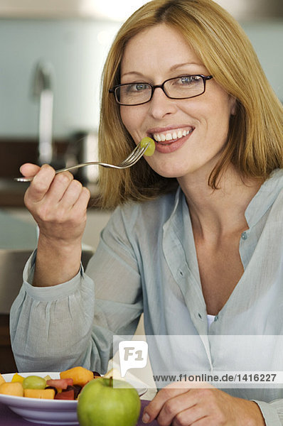 Smiling woman eating fruit salad