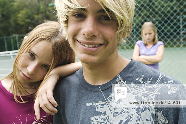 Lächelnde Teenager schauen in die Kamera  Teenagermädchen mit gekreuzten Armen im Hintergrund  draußen