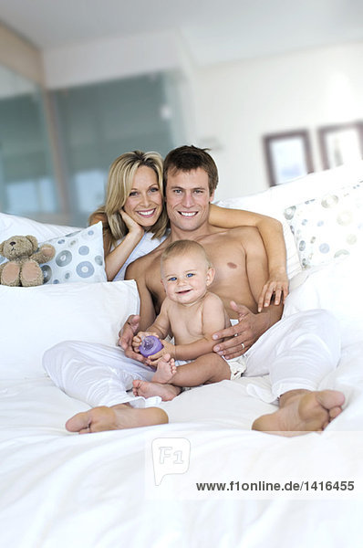 Young couple and baby in living room  looking at the camera  indoors