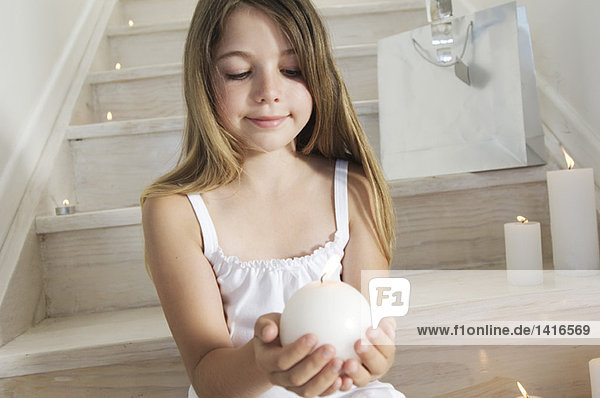 Christmas  little girl sitting indoors  holding a candle  indoors
