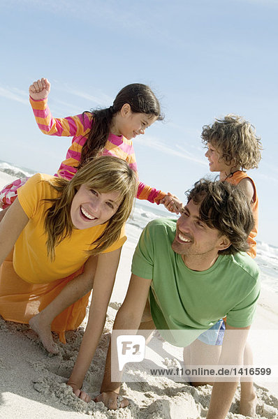Eltern und zwei Kinder beim Spielen am Strand  im Freien