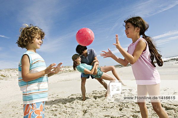 Eltern und zwei Kinder beim Spielen am Strand  im Freien