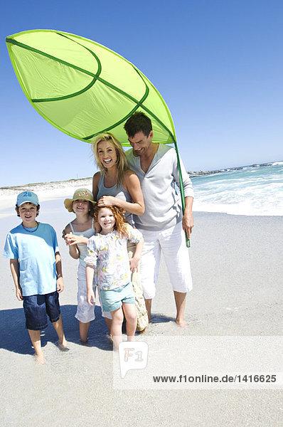 Eltern und drei Kinder am Strand posieren für die Kamera  im Freien
