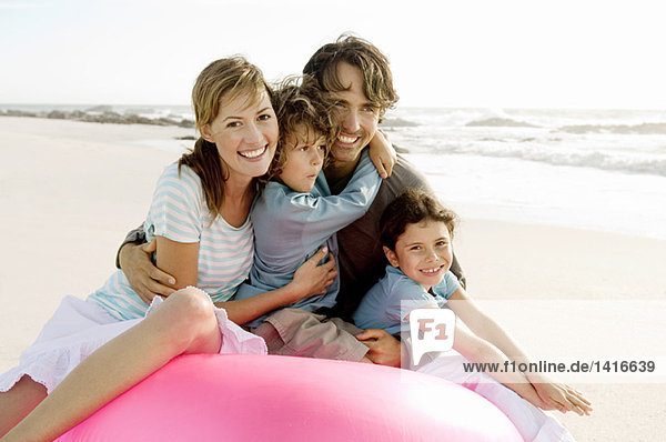 Parents and two children sitting on the beach  posing for the camera  outdoors