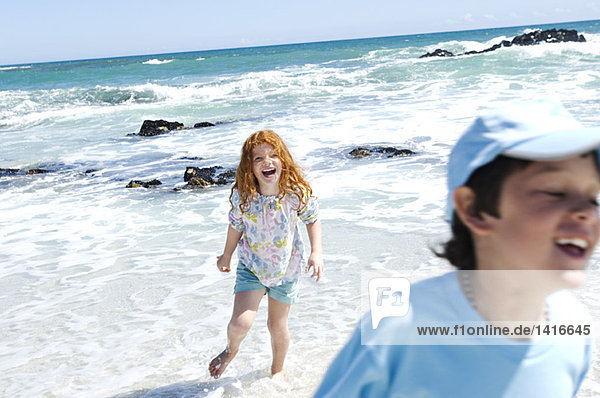 Boy and little girl walking on the beach  outdoors