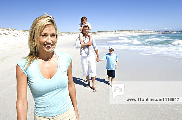 Eltern und zwei Kinder laufen am Strand  Mann trägt Tochter auf den Schultern  im Freien