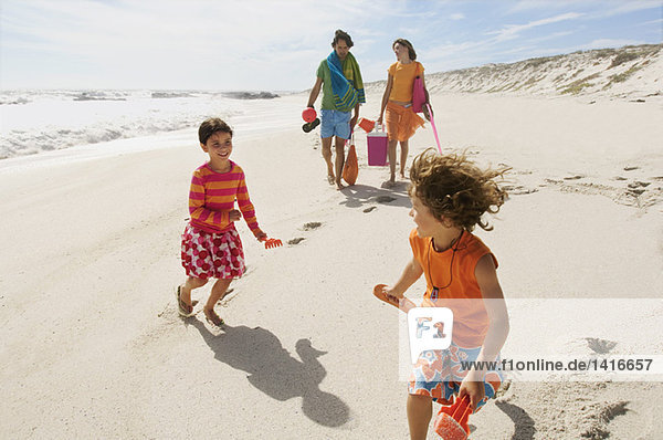 Eltern und zwei Kinder beim Spaziergang am Strand  im Freien