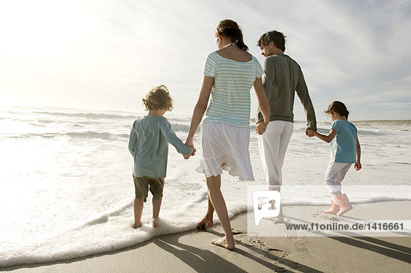 Parents and two children walking on the beach  rear view  outdoors