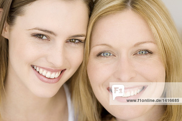 Porträt von zwei Frauen  die für die Kamera lächeln  drinnen