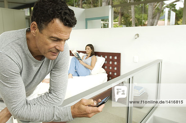 Paar im Schlafzimmer  Mann sucht seine Zelle  Frau liest Magazin  drinnen