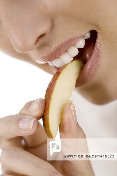 Porträt einer jungen Frau  die ein Stück Apfel isst  drinnen