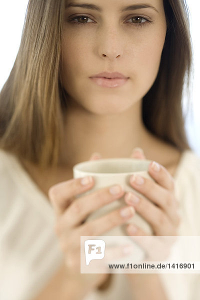 Porträt einer jungen Frau  die eine Tasse hält  drinnen