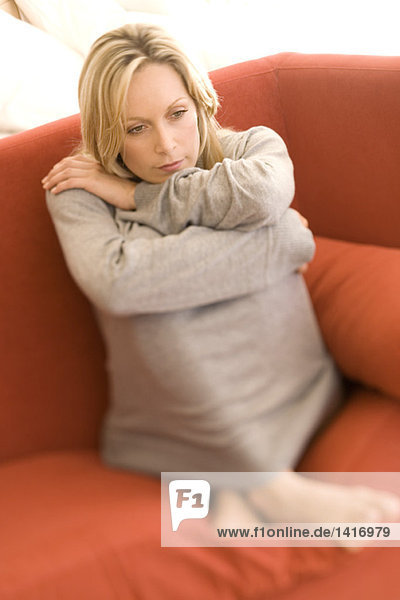 Junge denkende Frau auf einem Sofa sitzend