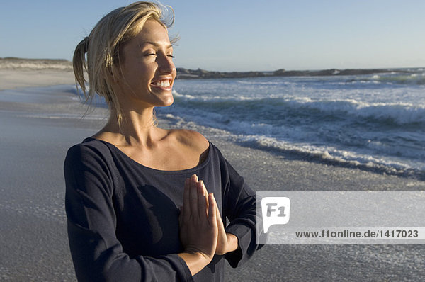 Young woman in yoga attitude on the beach  outdoors
