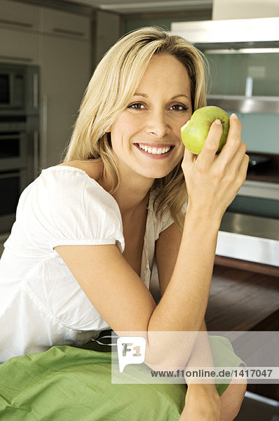 Junge lächelnde Frau beim Essen eines Apfels