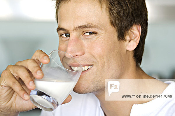 Porträt eines jungen Mannes  der ein Glas Milch trinkt.