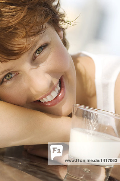 Porträt einer jungen lächelnden Frau  Glas Milch