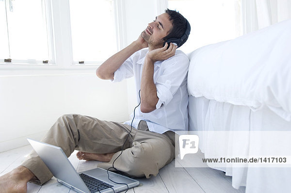 Young man listening to music with laptop