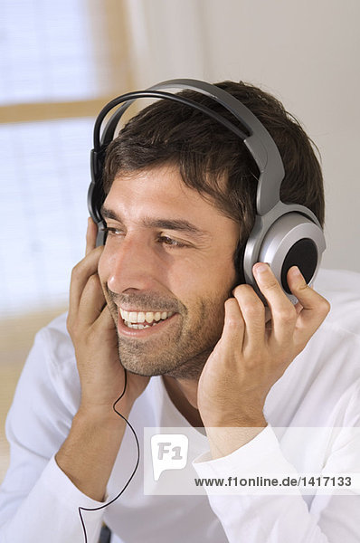 Porträt eines jungen Mannes  der mit Kopfhörern Musik hört.