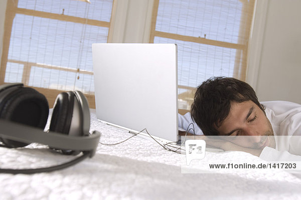 Junger Mann schläft vor dem Laptop