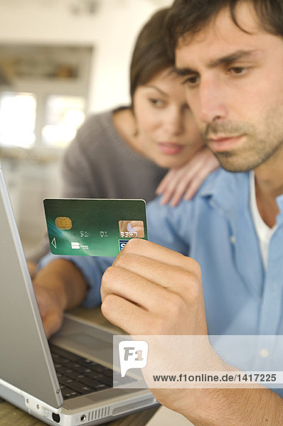 Young couple using credit card on internet