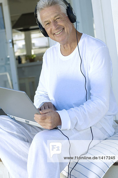 Lächelnder Mann mit Kopfhörer über Laptop