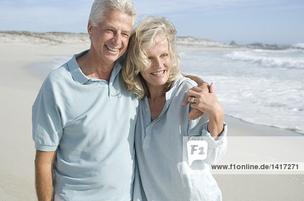 Lächelndes Paar  das sich am Strand umarmt.