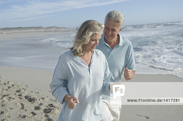 Smiling couple running on the beach