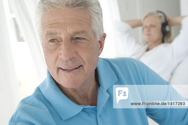 Couple in bedroom  portrait of man  woman listening to music with headphones in background