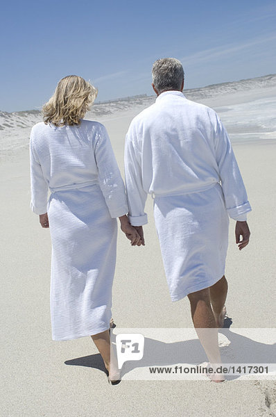 Couple in bathrobe walking on the beach  rear view