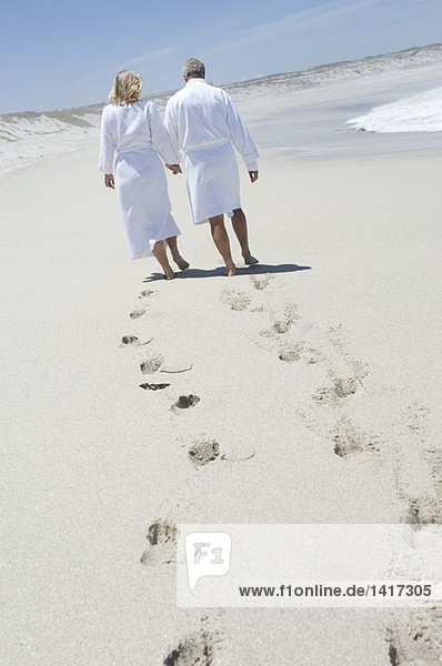 Couple in bathrobe walking on the beach  rear view
