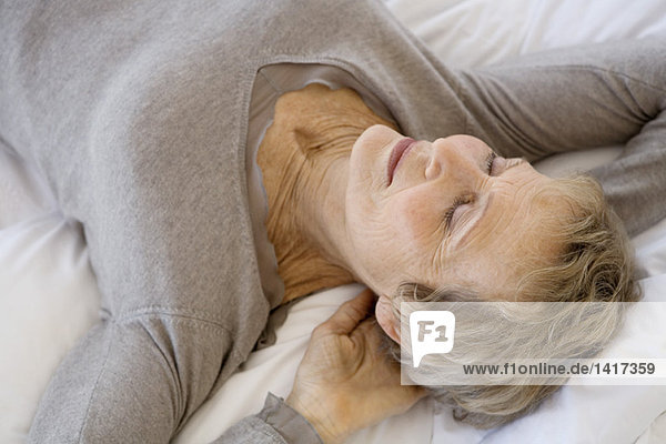 Senior woman sleeping  hands behind head