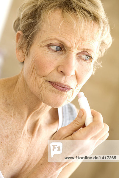 Portrait of senior woman using lipstick