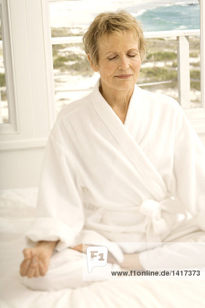 Senior woman sitting cross-legged on bed