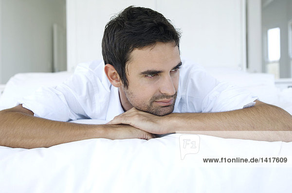 Young thinking man lying on bed